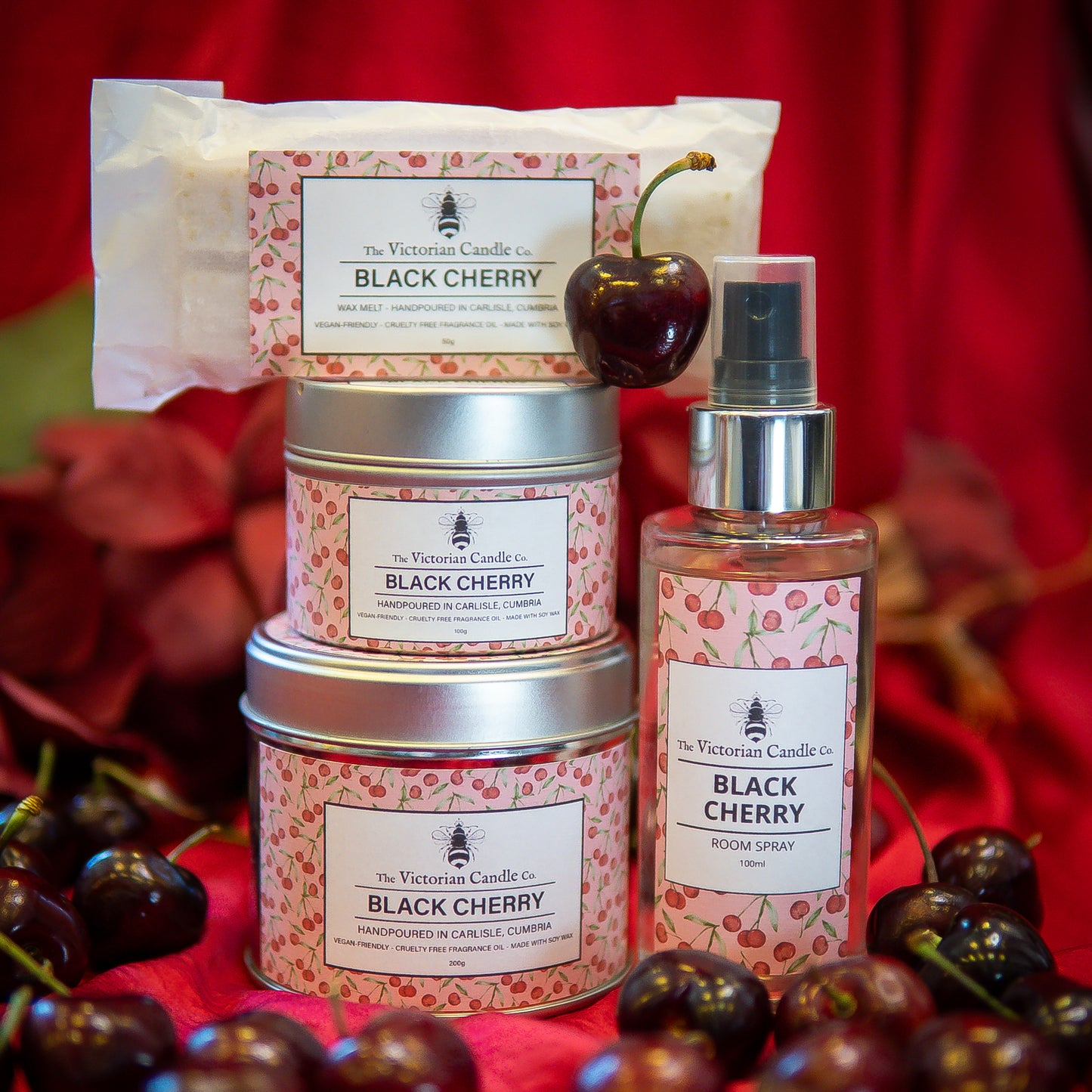 The Victorian Candle Co. Black Cherry Collection Box: includes three scented candle tins, a bar soap, and a room spray—an elegant gift set inspired by fresh cherries and perfect for any occasion.