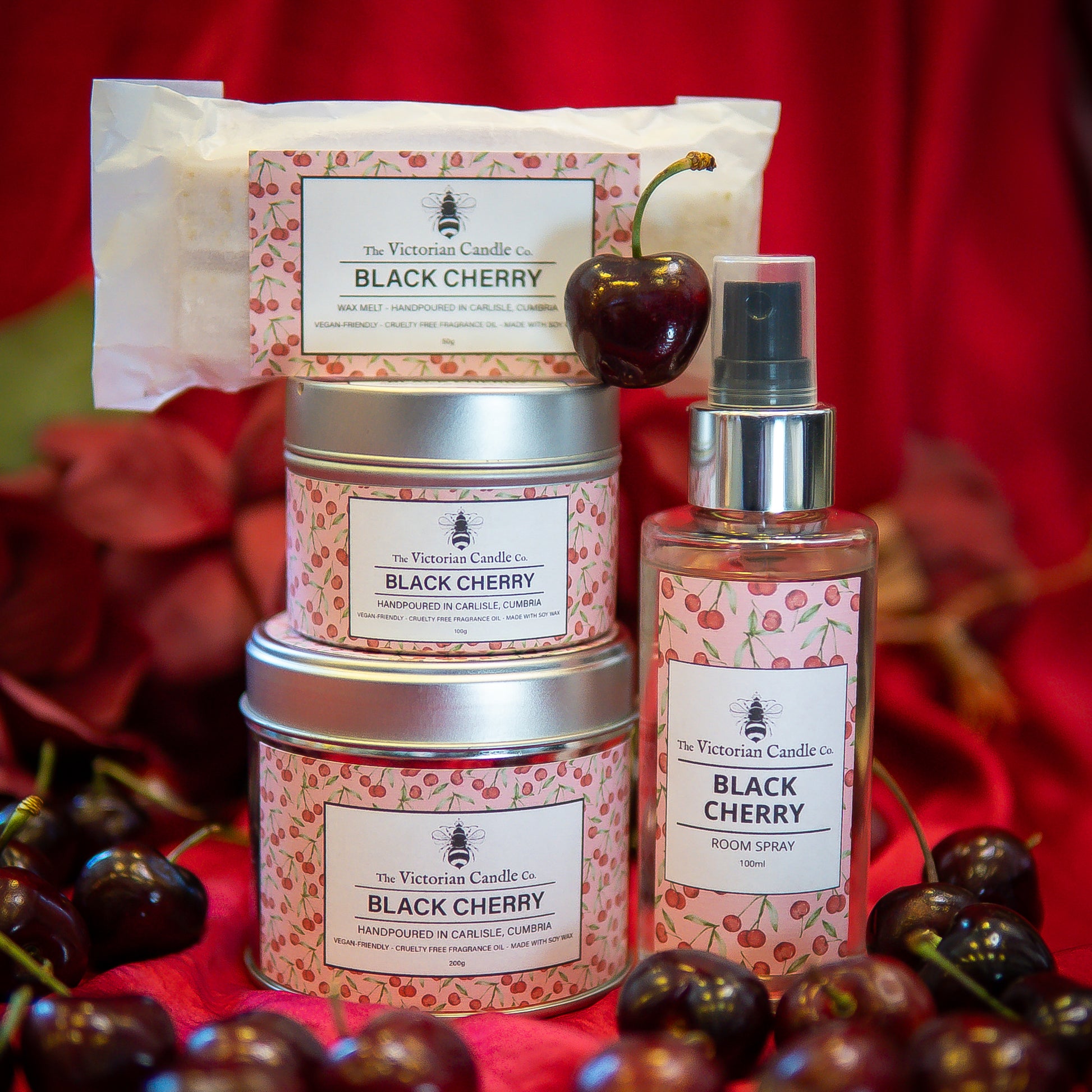 The Victorian Candle Co. Black Cherry Collection Box: includes three scented candle tins, a bar soap, and a room spray—an elegant gift set inspired by fresh cherries and perfect for any occasion.