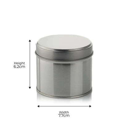 The Victorian Candle Co.'s (Large) Fresh Cotton Scented Candle is housed in a silver cylindrical metal tin with a lid, measuring 6.2 cm in height and 7.7 cm in width. This recyclable container holds a candle crafted from soy vegan wax. The image features arrows to clearly indicate the dimensions for accuracy.