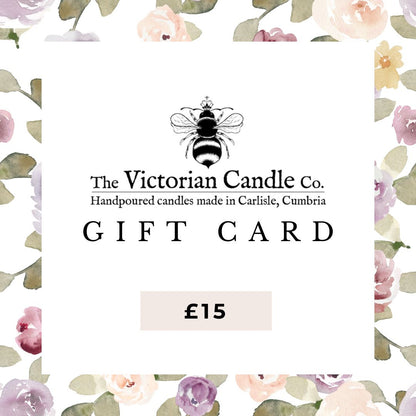 A £15 gift card for The Victorian Candle Co., adorned with a bee logo and a floral watercolor border. The text highlights "Handpoured candles made in Carlisle, Cumbria" and offers a variety of scent options.