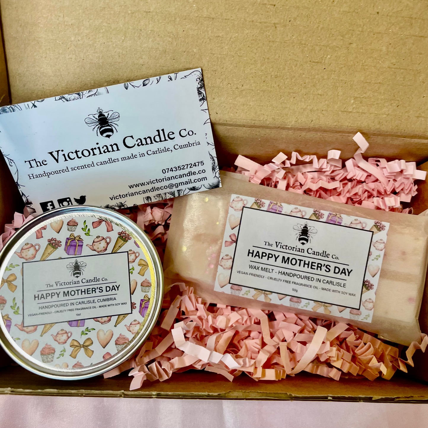 The Victorian Candle Co.s Mothers Day Mini Gift Box includes a Fresh Cotton Wax Melt and a Black Cherry Candle tin labeled Happy Mothers Day, nestled in pink shredded paper with a business card. Perfect for Mothers Day!.