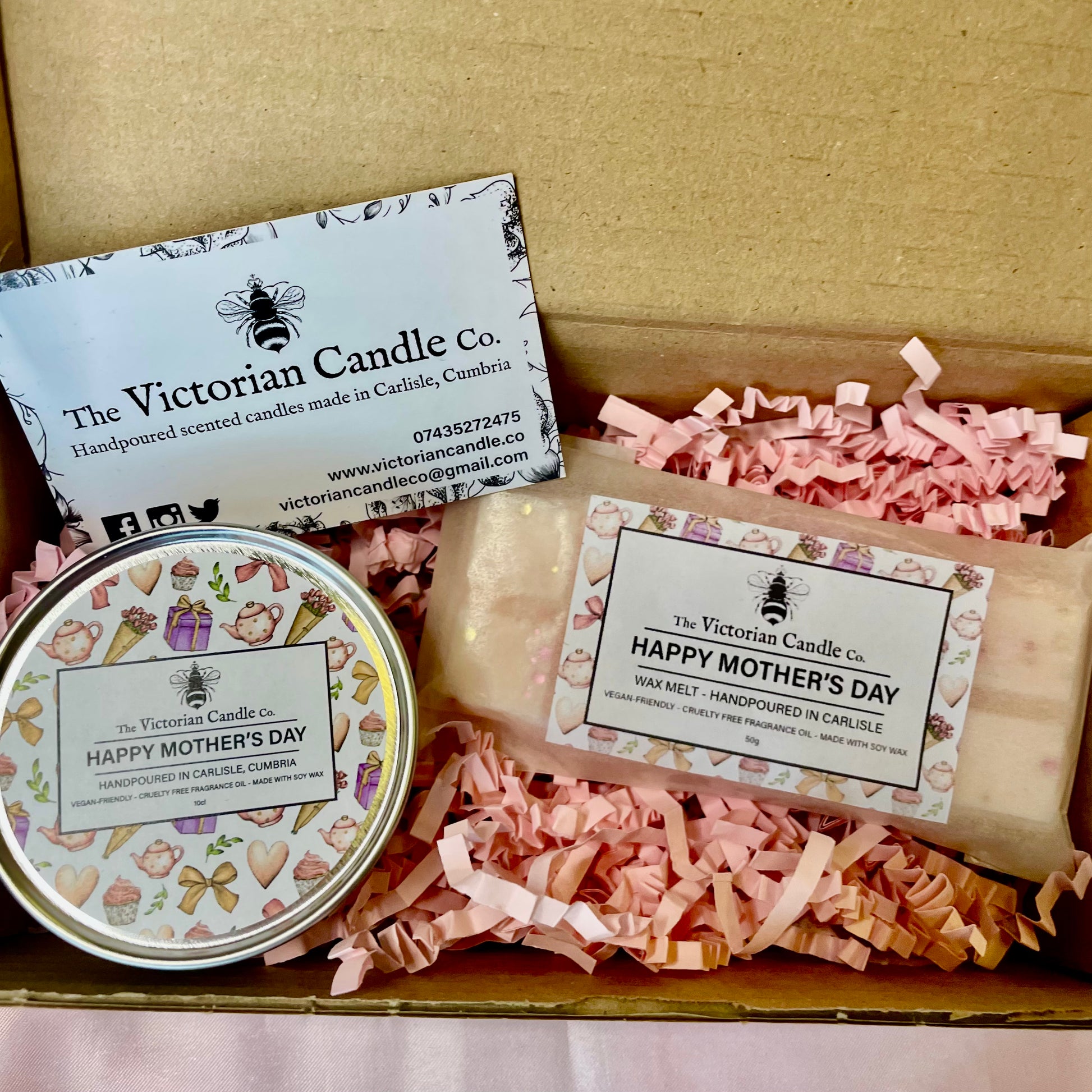 The Victorian Candle Co.s Mothers Day Mini Gift Box includes a Fresh Cotton Wax Melt and a Black Cherry Candle tin labeled Happy Mothers Day, nestled in pink shredded paper with a business card. Perfect for Mothers Day!.