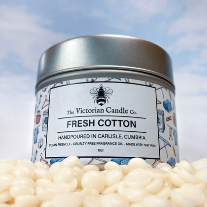 The Fresh Cotton - Scented Candle - 100ml Tin by The Victorian Candle Co. features a silver lid and an endearing bee illustration on its label, adorned with icons of clothes and detergent. Hand-poured in Carlisle, Cumbria, this candle is made with 100% soy vegan-friendly wax housed in recyclable tins, combining sustainability with elegance.